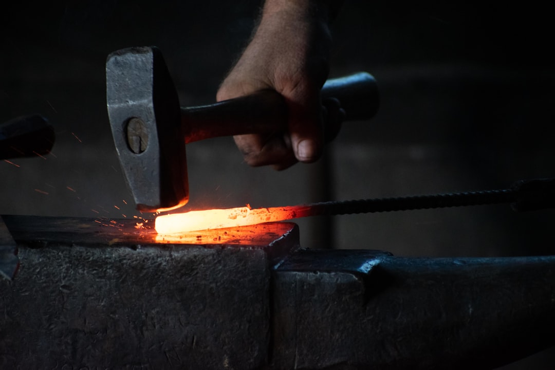 Forgeron au travail, martelant du fer incandescent à la forge